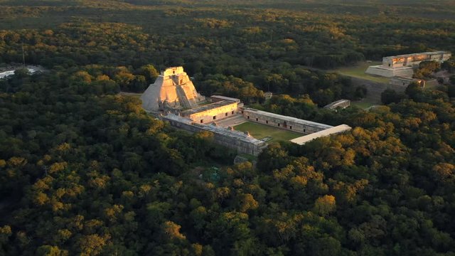 Aerial, drone shot, tilting towards the Uxmal ruins, Pyramid of the Magician, on a sunny evening, in Yucatan, Mexico