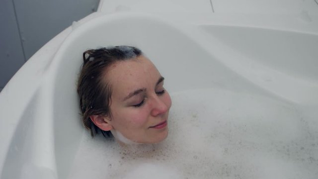 Woman lying in bath with closed eyes. Relax and pampering skin concept.