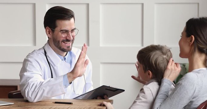 Happy friendly male pediatrician talk give high five kid patient