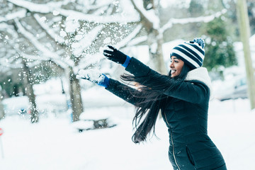Happy Indian woman playing with snow in the park.
