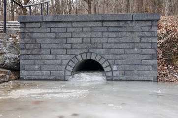 Outdoor water passage through a wall frozen and blocked by ice