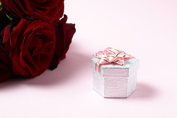 red roses with gift box on pink background. copy space. romance and love concept.