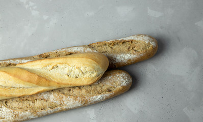 Three baguettes lying on top of each other on a gray background. Whole grain baguette. Place for...