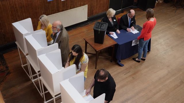 Voters voting at Polling Place / Station. Aerial view from above. People Stood at booths and post Ballot papers in Box