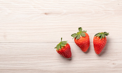 Three strawberries on wood background