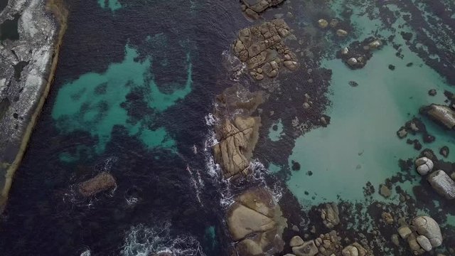 Plano de drone con grupo de personas nadando en el mar cerca de una playa de agua cristalina 4K