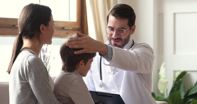 Happy caring male doctor encouraging kid boy patient at checkup