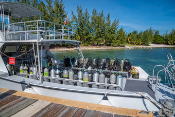 Dive boat with tanks and scuba gear docked by tropical beach