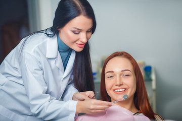 Young beautiful woman with beautiful white teeth sitting on a dental chair. Portrait of a woman with toothy smile sitting during examination at the dental office