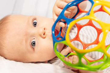 Beautiful little baby boy play with colorful vivid ball toy and look to camera close-up shoot