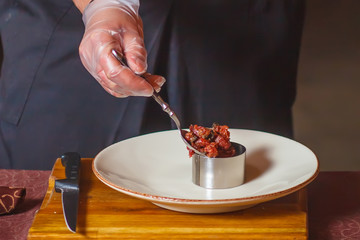 Close-up. Hands in the frame. Chef pours the ingredients into the form.