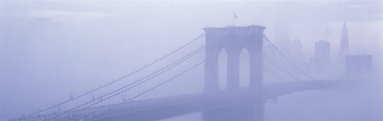 This is the Brooklyn Bridge over the East River. There is a morning Fog enveloping the bridge and city, causing Manhattan to look like the Emerald City in the Land of Oz.