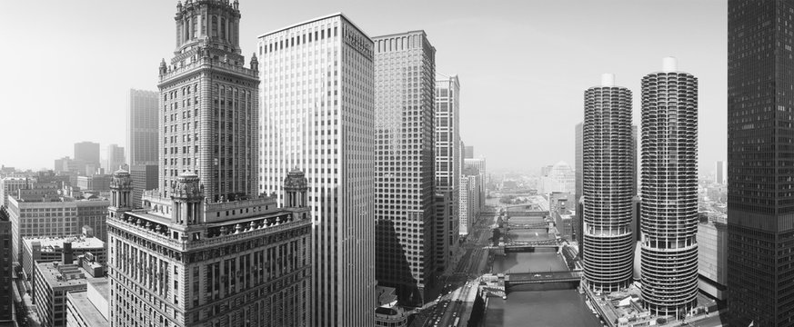 This is a view looking over the Chicago River. The Marina Tower Apartments, the Wrigley Building and the skyline surround the river. It is a black and white shot.