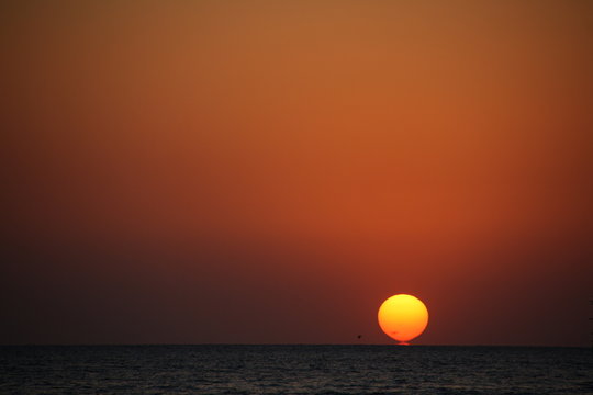 Sunset over the horizon of calm sea © Stavros