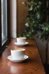 Coffee cups on wooden ledge with green plant - 316636136