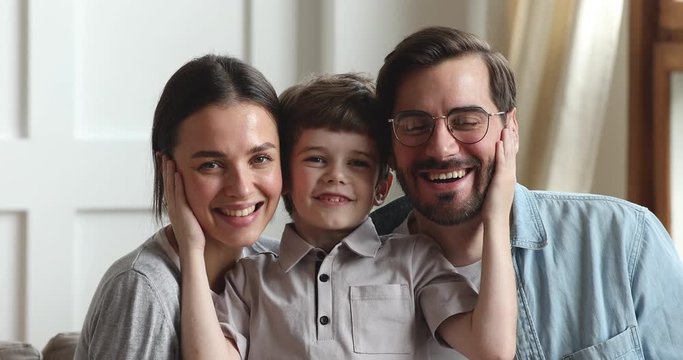 Cute small son and parents bonding looking at camera, portrait