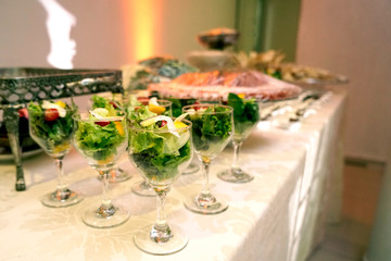finger food, table with small salads served in crystal bowls on blurred background with noise