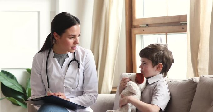 Professional female doctor talk to child boy patient hold toy