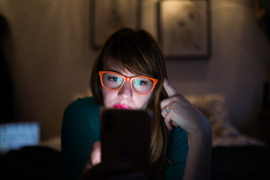Hipster girl with glasses looking at her mobile phone