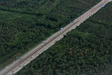Fototapeta na wymiar AERIAL, TOP DOWN: Cars and trucks drive on a highway speed road. Flying above busy space for text diagonal symmetry Commuters and travelers driving up and down asphalt road