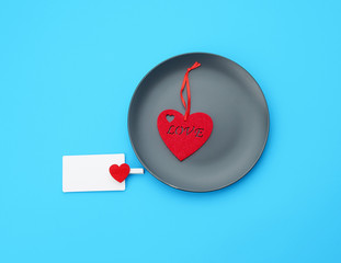 empty round gray plate and decorative red heart, next to an empty white business card