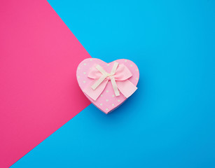 pink gift box in the form of a heart with a bow on a blue background