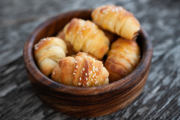 Croissants sprinkled with sesame seeds in a wooden basket. Close-up