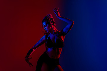 Fototapeta na wymiar Black dressed and braided hair woman dancing on a blue and red background.