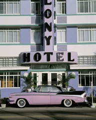 Fotobehang Dit is het Colony Hotel op de strip van South Beach Miami. Voor het hotel staat een paars-zwarte oldtimer geparkeerd. © spiritofamerica