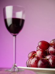 One glass of red wine and fresh juicy grapes, Purple background, Alcohol product. Still life.