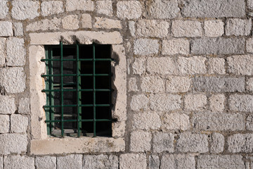 Fototapeta na wymiar Old window with bars, in an ancient medieval wall