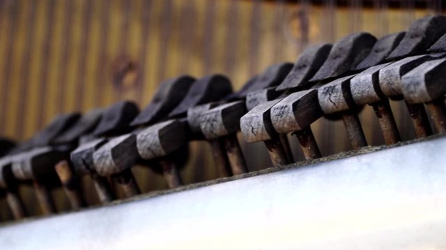 Old broken hammers of a deteriorated and abandoned piano, panning close up