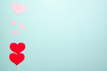 Plakat Hearts of different sizes fly up from a red paper heart on wooden stick on the left side on blue background. Valentines day concept. Flat lay top view with space for text banner