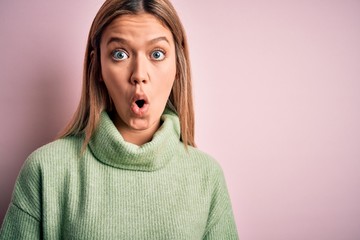 Young beautiful blonde woman wearing winter wool sweater over pink isolated background afraid and shocked with surprise expression, fear and excited face.