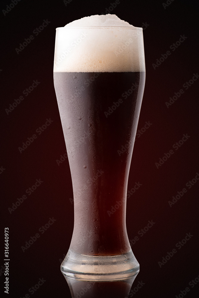 Wall mural glass of fresh beer dark background.