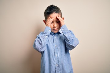 Young little boy kid wearing elegant shirt standing over isolated background with hand on head for pain in head because stress. Suffering migraine.