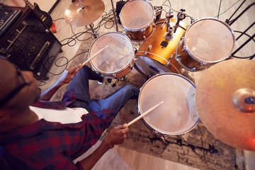 High angle portrait of young African-American man playing drums with contemporary music band during...