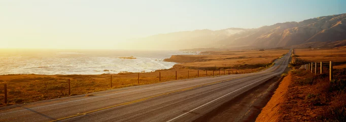 Foto op Canvas Dit is Route 1 ook wel bekend als de Pacific Coast Highway. De weg ligt naast de oceaan met de bergen in de verte. De weg gaat in het oneindige de zonsondergang in. © spiritofamerica