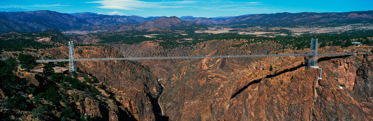 This is the Royal Gorge Bridge which is the world's highest suspension bridge. It is 1053 Ft. above the Arkansas River. Mountains are in the background with red rock below the bridge.