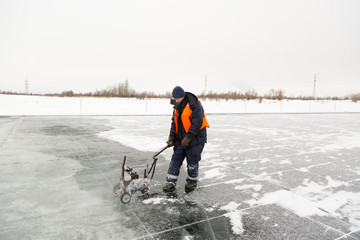 Worker cuts out ice blocks in size on the ice of a frozen lake