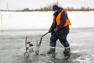 Worker cuts out ice blocks in size on the ice of a frozen lake