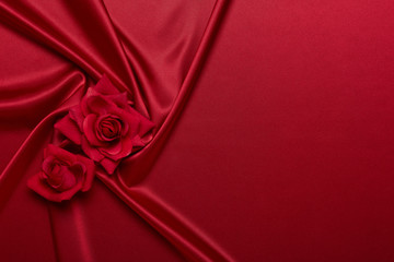 Abstract background from red silk (satin) and roses. Fabric texture with draped. Copy space. Element design. Valentine's day.