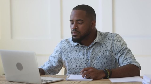 Concentrated young african ethnicity guy watching educational webinar.