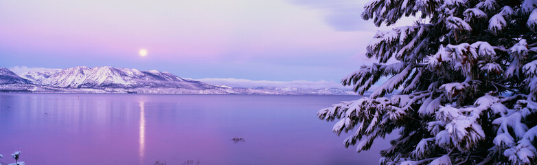 This is Lake Tahoe after a winter snow storm. There is a full moon rising over the lake and the...