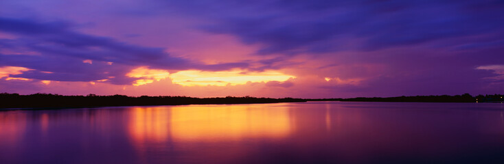 Obraz premium This is the ocean and Pine Island at sunset. There is a pinkish purple cast in the sky that is reflected in the water. The nearby land is in silhouette.