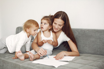Cute family in a room. Lady in a white shirt. Mother with cute children