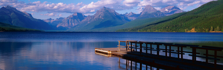 This is a boat dock at Lake McDonald. The blue water of the lake surrounds the dock with mountains...