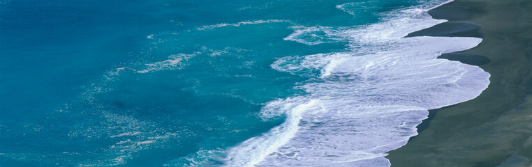 This is the turquoise water of the Atlantic Ocean sweeping onto the beach beneath the Pacific Coast Highway.