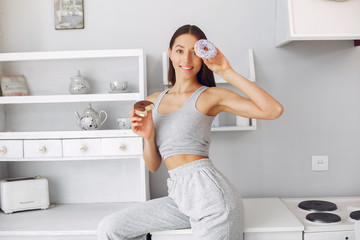 Girl in a white shirt. Lady in a kitchen. Girl with a donut