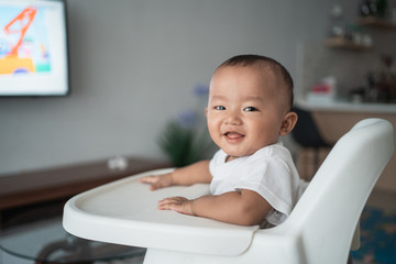 happy asian baby boy sitting on high chair smiling